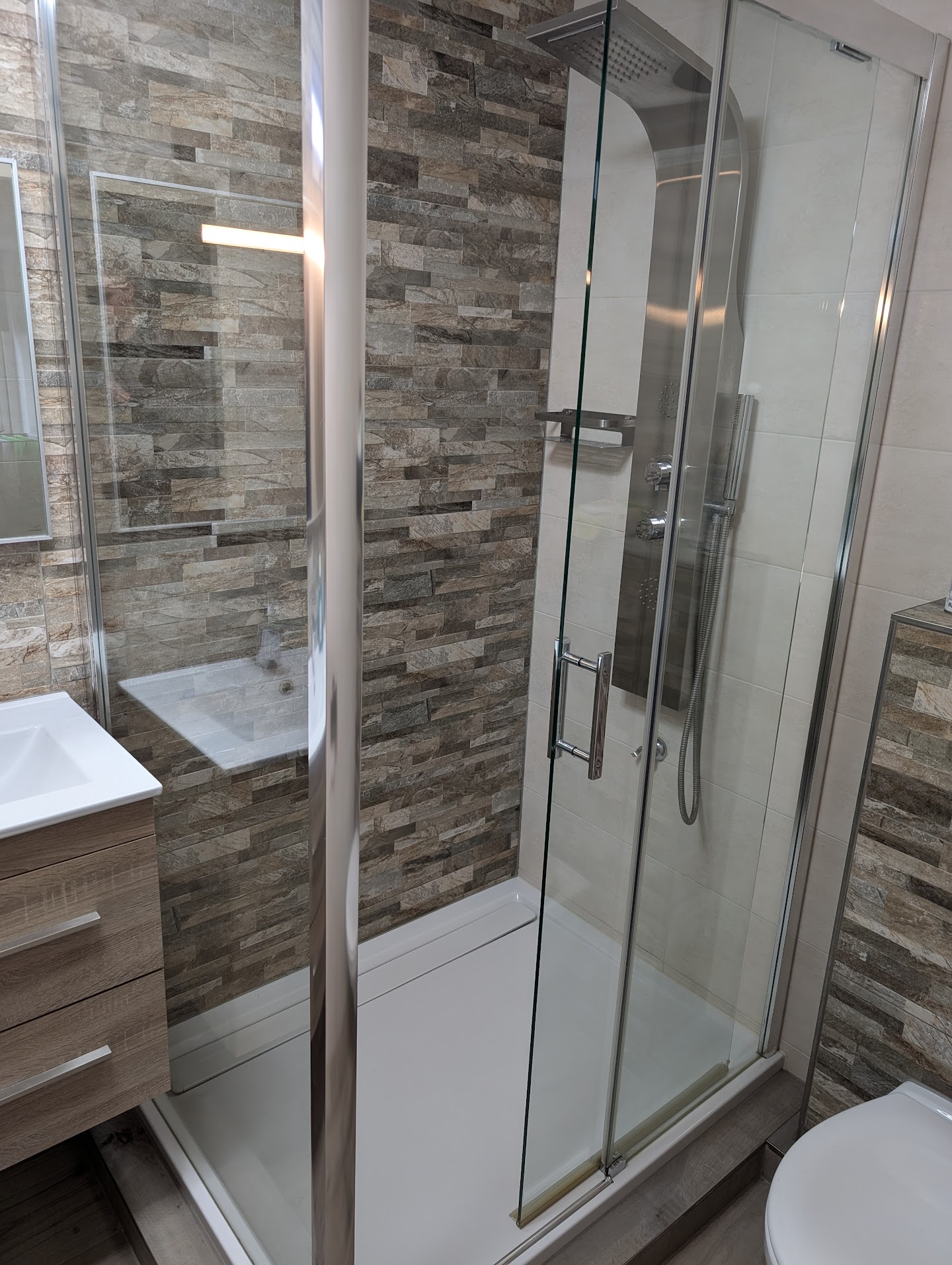 Gecoate douchehoek met glazen deur en stenen wand
